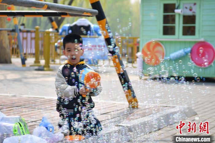 4月4日，小朋友在北京陶然亭公园玩泡泡枪。　中新社记者 田雨昊 摄