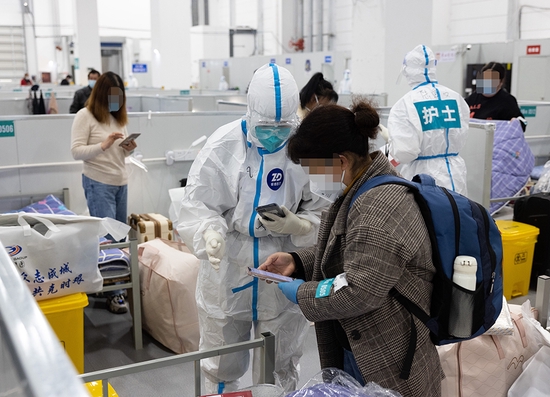 2022年4月6日，在上海临港方舱医院，来自复旦大学附属华山医院的医护人员为新转运过来的感染者安排床位。新华社发（华山医院 供图）