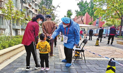 在核酸检测现场,北京市石景山区检察院干警为群众测量体温。记者闫昭　通讯员成于庆摄